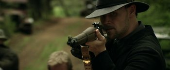 Movie still from “In Dubious Battle” (2016), directed by James Franco – A man in a hat and a black hat holding a rifle; Close Up shot, Over the shoulder angle