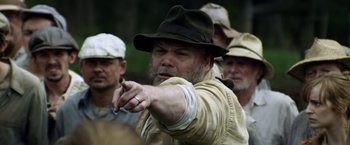 Movie still from “In Dubious Battle” (2016), directed by James Franco – A man in a hat pointing at something; Close Up shot, Over the shoulder angle