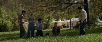 Movie still from “In Dubious Battle” (2016), directed by James Franco – A group of people sitting in the grass; Wide shot, Over the shoulder angle