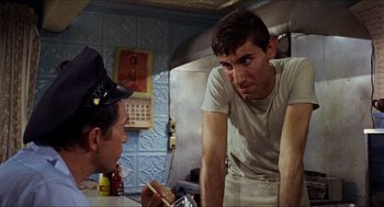 Movie still from “In the Heat of the Night” (1967), directed by Norman Jewison – Two men in a kitchen talking to each other; Medium shot, Over the shoulder angle