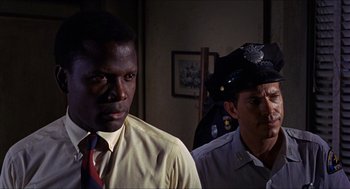 Movie still from “In the Heat of the Night” (1967), directed by Norman Jewison – Two police officers standing next to each other in a room; Close Up shot, Over the shoulder angle