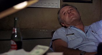 Movie still from “In the Heat of the Night” (1967), directed by Norman Jewison – A man laying on the ground with a dollar bill in his hand; Medium shot, Low angle