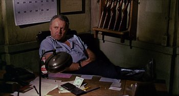 Movie still from “In the Heat of the Night” (1967), directed by Norman Jewison – An older man sitting at a table with money on the table; Medium shot, High angle