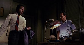 Movie still from “In the Heat of the Night” (1967), directed by Norman Jewison – Two men standing next to each other in a dark room; Medium shot, Low angle