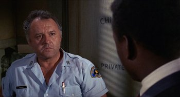 Movie still from “In the Heat of the Night” (1967), directed by Norman Jewison – A police officer is looking at a man in the mirror; Close Up shot, Over the shoulder angle