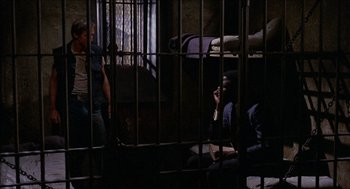 Movie still from “In the Heat of the Night” (1967), directed by Norman Jewison – A group of people sitting in a jail cell; Wide shot, High angle