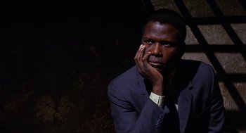 Movie still from “In the Heat of the Night” (1967), directed by Norman Jewison – A man in a suit and tie holding his hand to his face; Close Up shot, High angle