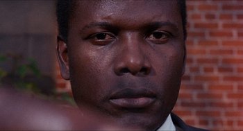 Movie still from “In the Heat of the Night” (1967), directed by Norman Jewison – A man's face in front of a brick wall; Close Up shot, Over the shoulder angle