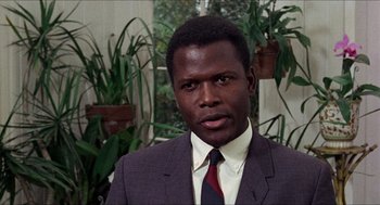 Movie still from “In the Heat of the Night” (1967), directed by Norman Jewison – A man wearing a suit and tie in front of plants; Close Up shot, Over the shoulder angle