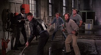 Movie still from “In the Heat of the Night” (1967), directed by Norman Jewison – A group of men are playing a game in a warehouse; Wide shot, High angle