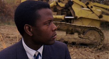 Movie still from “In the Heat of the Night” (1967), directed by Norman Jewison – A man wearing a suit and tie looking to his left; Close Up shot, Over the shoulder angle