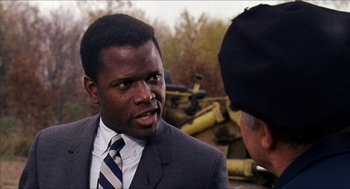 Movie still from “In the Heat of the Night” (1967), directed by Norman Jewison – A man wearing a suit and tie talking to another man; Close Up shot, Over the shoulder angle