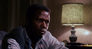 Movie still from “In the Heat of the Night” (1967), directed by Norman Jewison – A person sitting in a room near a lamp; Close Up shot, Over the shoulder angle