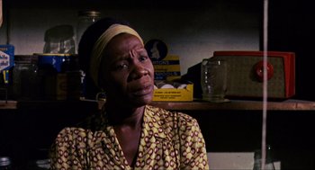 Movie still from “In the Heat of the Night” (1967), directed by Norman Jewison – An older black woman wearing a head scarf; Close Up shot, High angle