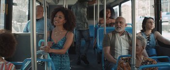 Movie still from “In the Heights” (2021), directed by Jon M. Chu – A group of people riding on a blue bus together; Medium shot, Over the shoulder angle