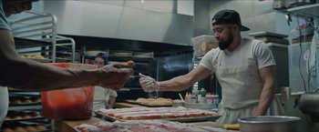 Movie still from “In the Heights” (2021), directed by Jon M. Chu – A man in a kitchen making a pepperoni pizza; Medium shot, Low angle