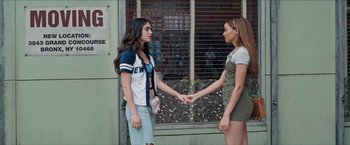 Two young women holding hands in front of a building