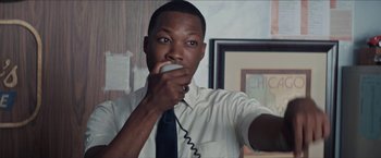 Movie still from “In the Heights” (2021), directed by Jon M. Chu – A man holding a phone up to his mouth; Close Up shot, High angle