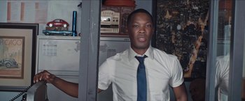 Movie still from “In the Heights” (2021), directed by Jon M. Chu – A man wearing a white shirt and a blue tie; Medium shot, Low angle