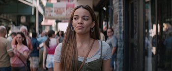 Movie still from “In the Heights” (2021), directed by Jon M. Chu – A woman with long brown hair wearing a white striped shirt; Close Up shot, Over the shoulder angle