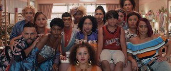 Movie still from “In the Heights” (2021), directed by Jon M. Chu – A group of people sitting in a room together; Medium shot, High angle