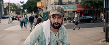 Movie still from “In the Heights” (2021), directed by Jon M. Chu – A man with a beard wearing a hat and a towel; Close Up shot, Over the shoulder angle