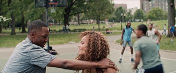 Movie still from “In the Heights” (2021), directed by Jon M. Chu – A young woman is hugging a young man in a park; Medium shot, Over the shoulder angle