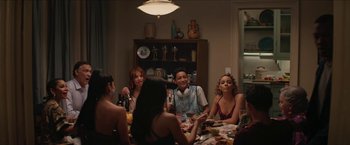 Movie still from “In the Heights” (2021), directed by Jon M. Chu – A group of people sitting around a table with food; Medium shot, Over the shoulder angle
