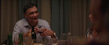 A man sitting at a dinner table holding a cell phone