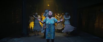 Movie still from “In the Heights” (2021), directed by Jon M. Chu – An older woman standing in front of a group of people; Wide shot, Low angle