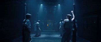 Movie still from “In the Heights” (2021), directed by Jon M. Chu – A group of men standing in a dark room; Wide shot, Low angle