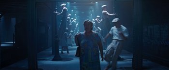 Movie still from “In the Heights” (2021), directed by Jon M. Chu – A woman walking down a hallway with a bunch of people in the background; Wide shot, Low angle