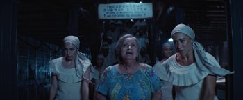 Movie still from “In the Heights” (2021), directed by Jon M. Chu – An older woman standing in front of a group of people; Medium shot, Low angle