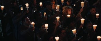 Movie still from “In the Heights” (2021), directed by Jon M. Chu – A group of people holding lit candles in a dark room; Wide shot, High angle