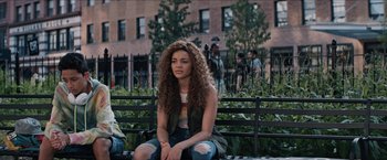 Movie still from “In the Heights” (2021), directed by Jon M. Chu – A woman sitting on top of a wooden bench; Medium shot, Over the shoulder angle