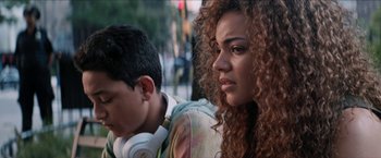 Movie still from “In the Heights” (2021), directed by Jon M. Chu – Two people sitting next to each other on the street; Close Up shot, Over the shoulder angle