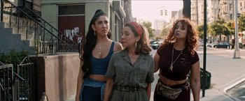 Movie still from “In the Heights” (2021), directed by Jon M. Chu – A group of women standing next to each other on a sidewalk; Medium shot, Over the shoulder angle