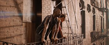 Movie still from “In the Heights” (2021), directed by Jon M. Chu – A man and a woman standing next to a railing; Medium shot, Low angle