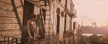 Movie still from “In the Heights” (2021), directed by Jon M. Chu – A man and a woman standing on a fire escape; Wide shot, Low angle
