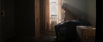 Movie still from “In the Heights” (2021), directed by Jon M. Chu – A man sitting in a chair looking out of a window; Medium shot, Low angle