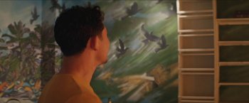 A man standing in front of a painting of birds