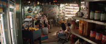 Movie still from “In the Heights” (2021), directed by Jon M. Chu – A group of people sitting around in a room; Wide shot, High angle