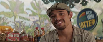 Movie still from “In the Heights” (2021), directed by Jon M. Chu – A man wearing a hat and smiling for the camera; Close Up shot, Over the shoulder angle