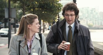 Movie still from “In the Loop” (2009), directed by Armando Iannucci – A man and a woman walking down a street; Medium shot, Over the shoulder angle