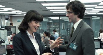 Movie still from “In the Loop” (2009), directed by Armando Iannucci – A man and a woman talking to each other in an office setting; Medium shot, Over the shoulder angle