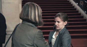Movie still from “In the Loop” (2009), directed by Armando Iannucci – Two women in business suits talking on the stairs; Medium shot, Over the shoulder angle