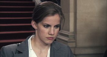 Movie still from “In the Loop” (2009), directed by Armando Iannucci – A woman in a gray jacket is looking down; Close Up shot, Over the shoulder angle