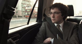 Movie still from “In the Loop” (2009), directed by Armando Iannucci – A man sitting in the back seat of a car looking out the window; Close Up shot, High angle