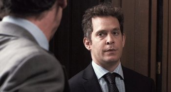 Movie still from “In the Loop” (2009), directed by Armando Iannucci – A man wearing a suit and tie looking at himself in the mirror; Close Up shot, Over the shoulder angle