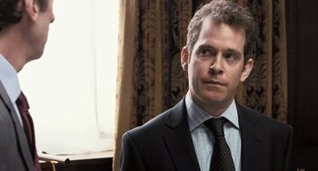 Movie still from “In the Loop” (2009), directed by Armando Iannucci – A person wearing a suit and tie; Close Up shot, Over the shoulder angle